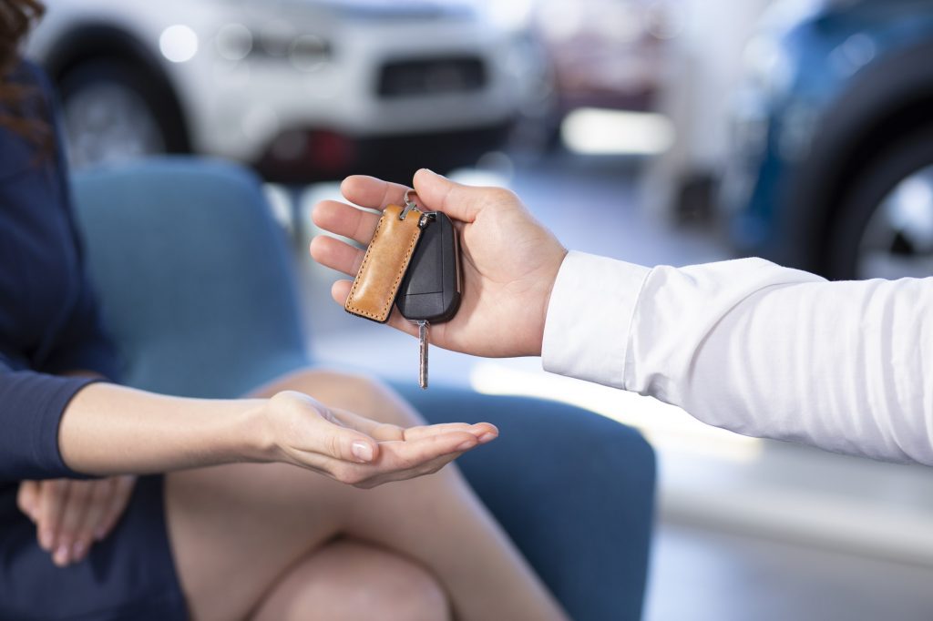 Close-up of a hand holding car keys and giving it to a buyer